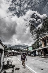 Old woman walking along the road while eruption of Merapi volcano