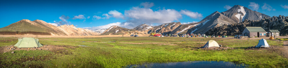Panoramic view of colorful volcanic Landmannalaugar region and camping site at blue sky in Iceland