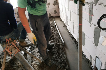 Employee performs sand-cement floor screed, Sand-cement floor screed for heating.