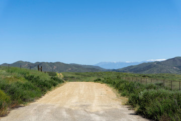 Dirt road in the country with snow capped mountains in the distance