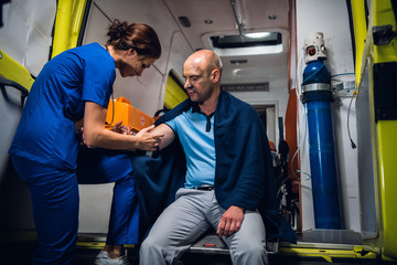 A female paramedic providing first aid to an injured man resqued from the fire, giving an injection