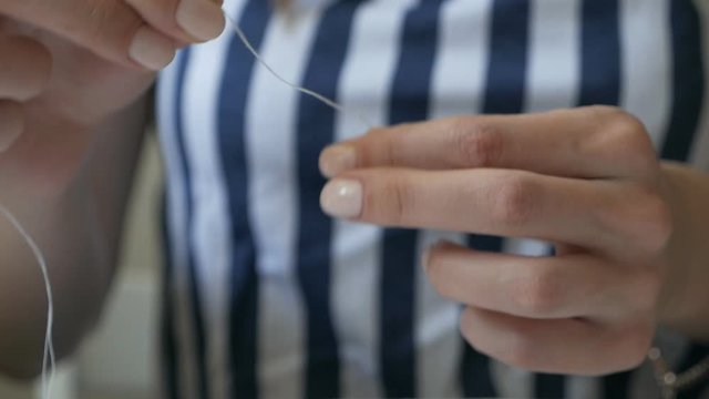 The seamstress knits the tip of the thread in a knot before sewing