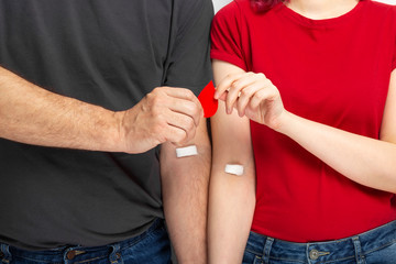 Blood donorship. Man in grey and woman in red T-shirt with hands taped patch after blood is handed...