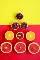Top view on circles of orange, red orange and grapefruit in the shape of a Christmas tree on a red and yellow background.