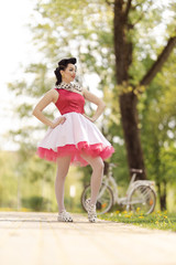 Retro style photo. A girl in a pink dress and hairstyle in the style of the 40-50s dances and poses...