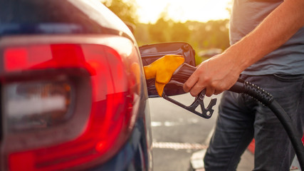 Pumping gas at gas pump. Closeup of man pumping gasoline fuel in car at gas station. Gas pump nozzle in the fuel tank of a blue car, refuel. Petrol pump filling