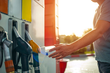 Man hand holding a fuel pump at a station. Detail of a hand holding a fuel pump at a station....