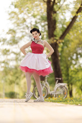 Retro style photo. A girl in a pink dress and hairstyle in the style of the 40-50s dances and poses...