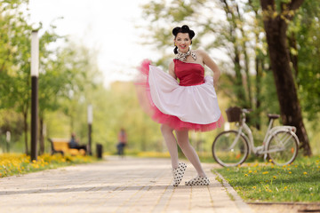 Retro style photo. A girl in a pink dress and hairstyle in the style of the 40-50s dances and poses...