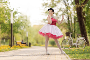 Retro style photo. A girl in a pink dress and hairstyle in the style of the 40-50s dances and poses...