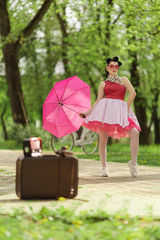 Retro style photo. A girl in a pink dress and hairstyle in the style of the 40-50s holds a pink...