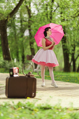 Retro style photo. A girl in a pink dress and hairstyle in the style of the 40-50s holds a pink...