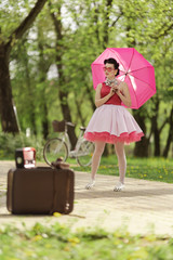 Retro style photo. A girl in a pink dress and hairstyle in the style of the 40-50s holds a pink...