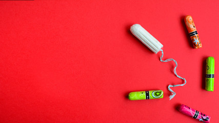 Protection of feminine hygiene. Cotton swab and multi-colored swabs in a package on a red background. Side space for text