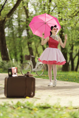 Retro style photo. A girl in a pink dress and hairstyle in the style of the 40-50s holds a pink...