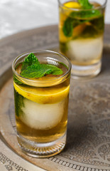 Refreshing glasses of tea with ice, mint and lemon wedges