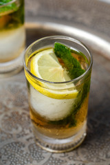 Refreshing glasses of tea with ice, mint and lemon wedges