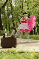Retro style photo. A girl in a pink dress and hairstyle in the style of the 40-50s holds a pink...