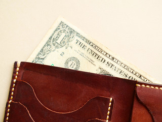 brown wallet with with one dollar on bright background. last money, poverty, unemployment, job loss, saving concept. Flat lay, close up