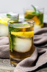 Refreshing glasses of tea with ice, mint and lemon wedges