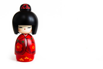 Kokeshi doll in red kimono. Still-life photo (taken on studio with white background and softbox) of a Japanese traditional doll isolated on white.