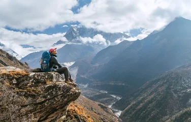 Papier Peint photo autocollant Ama Dablam Young hiker female backpacker sitting on the cliff edge and enjoying Ama Dablam 6,812m peak view during Everest Base Camp (EBC) trekking route near Phortse, Nepal. Active vacations image concept