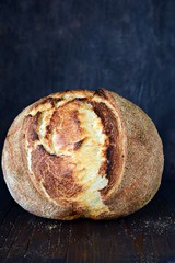 Homemade Freshly Baked Country Bread  made from wheat and whole grain flour on a dark background. French Freshly baked bread. Slicing homemade bread 