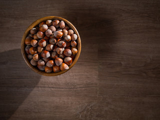 Obraz na płótnie Canvas Picture of a bowl full of hazelnuts on the brown wooden table.