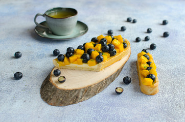 Homemade tarts with fresh mango and blueberries on blue backgraunde
