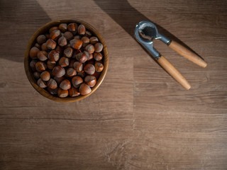Fototapeta na wymiar Picture of a bowl full of hazelnuts on the brown wooden table.