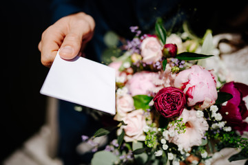 photo of a hand putting a card on a bouquet of flowers