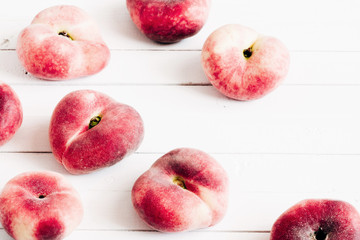 Ripe red peaches fruits on table. Peaches scattered on white wooden background. Flat lay, top view, copy space