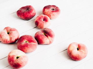 Ripe red peaches fruits on table. Peaches scattered on white wooden background. Flat lay, top view, copy space