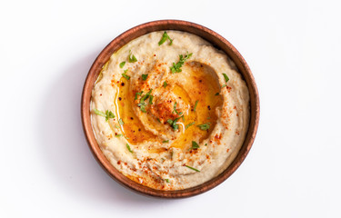 Homemade hummus with olive oil, herbs and paprika in a wooden bowl. white background.