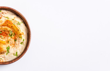 Homemade hummus with olive oil, herbs and paprika in a wooden bowl. white background.