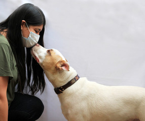 mujer con cubrebocas besando a su perro 