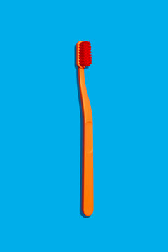 Modern Monochromatic Orange Hero Toothbrush Laying on Blue Background Isolated