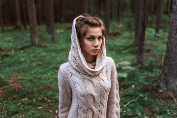 knitted jacket on a charming girl of European appearance. woman in the middle of a park, dense forest. alone model walks in a knitted sweater