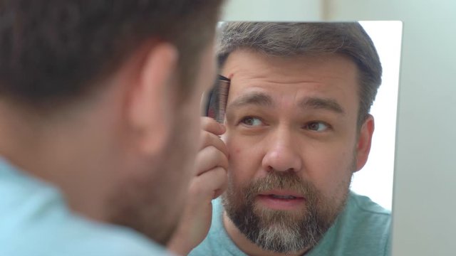 Man makes a haircut of beard and eyebrow razor.