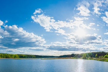 Landscape panorama of a beautiful blue large lake and sky with clouds with green forest on the shore. Pond 15, known as the 5 glade. Kyiv, Ukraine