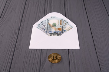 Dollar salary in white envelope or bitcoin golden coin concept