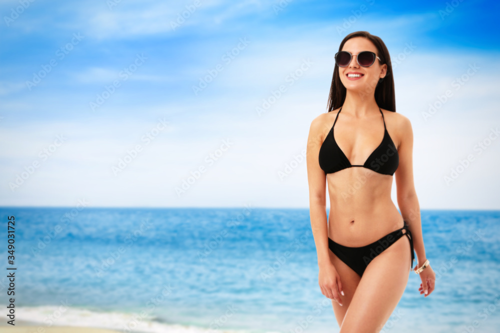 Sticker Pretty sexy woman with slim body in stylish black bikini near ocean on sunny day, space for text