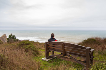 Hiker man resting on bench at the beach