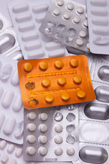 orange pill tablet container lying on grey and silver treatment packages scattered health cure vaccine 