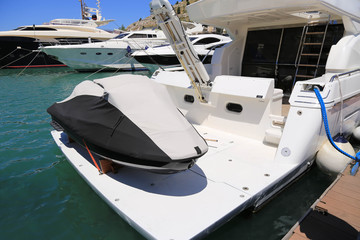 A rubber, latex high-speed motor boat stands on a large two-deck yacht in a sheathed form, secured with cables. The boat is closed from rain and wind, waiting for good weather and tourist season. Conc