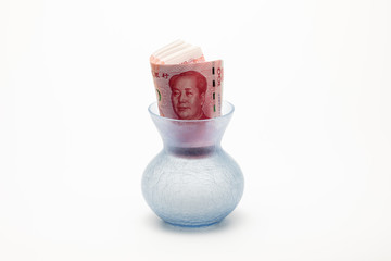 Rolled-up one hundred Chinese Reminbi yuan banknotes clogged at mouth of glass vase on white...