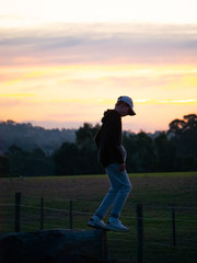 Man looking at sunset on farmland hillside
