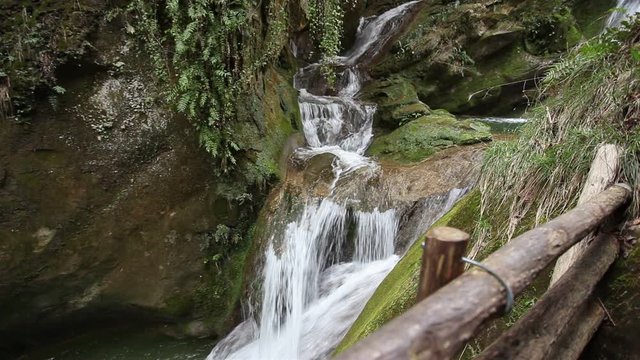 Small waterfalls in a rocky gorge full of vegetation, Caglieron Caves, Italy. Video that inspires tranquility and light-heartedness in nature