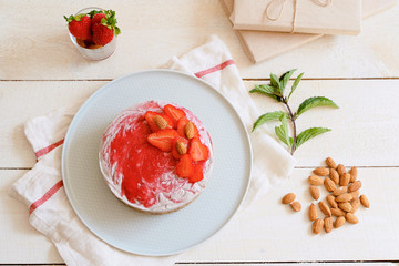 Strawberry cake with nuts, on a white wooden background