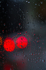 Window overlooking a rainy street. Gloomy evening weather with a view of the road. Drops on glass and bokeh from cars. Stock background for design